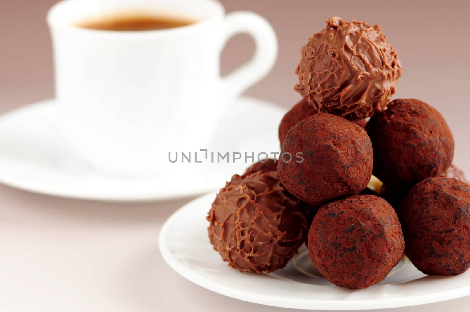 Gourmet chocolate truffles on a plate with a cup of coffee