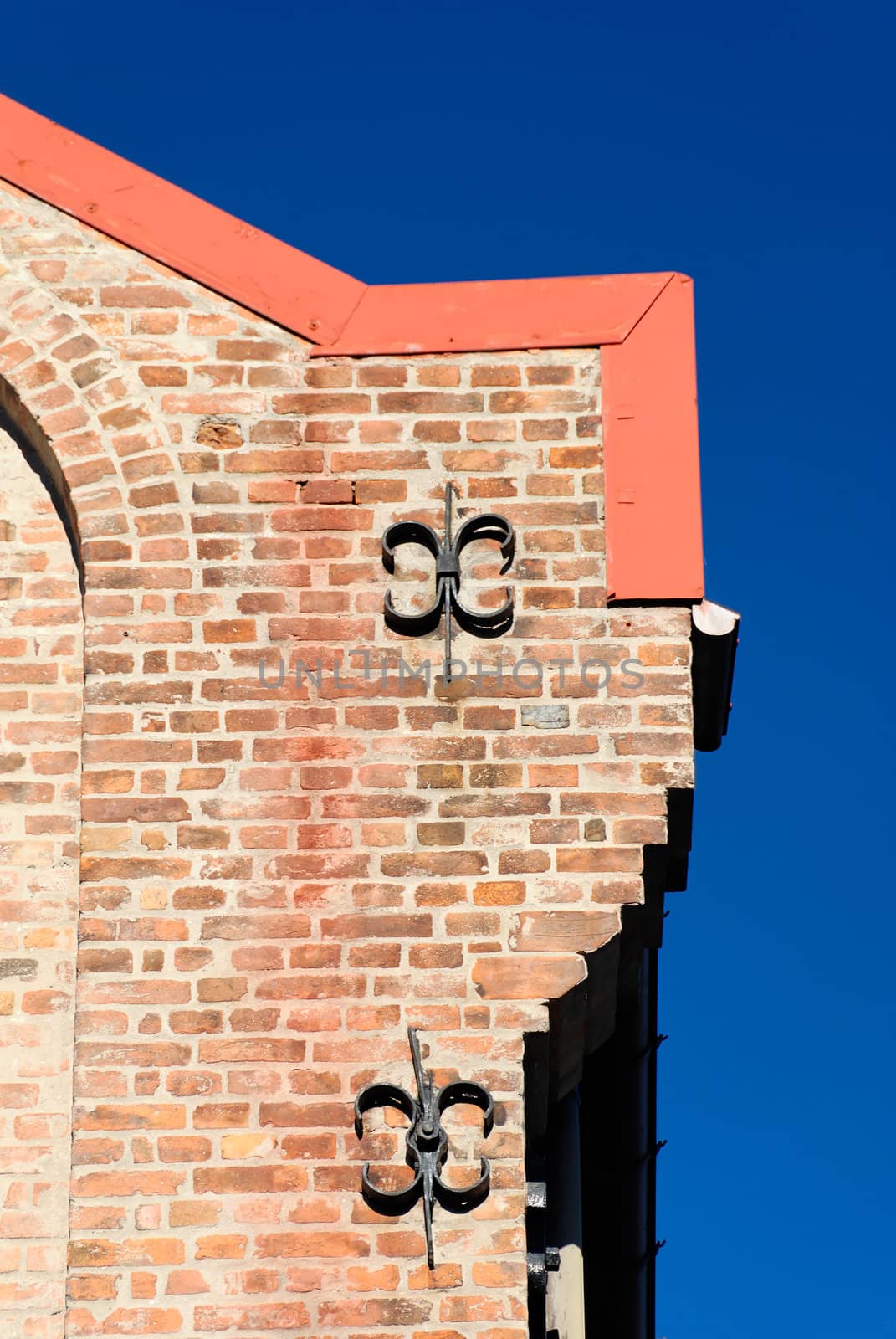 A corner of a brick house with two cast iron fixtures on polarised deep blue sky.
