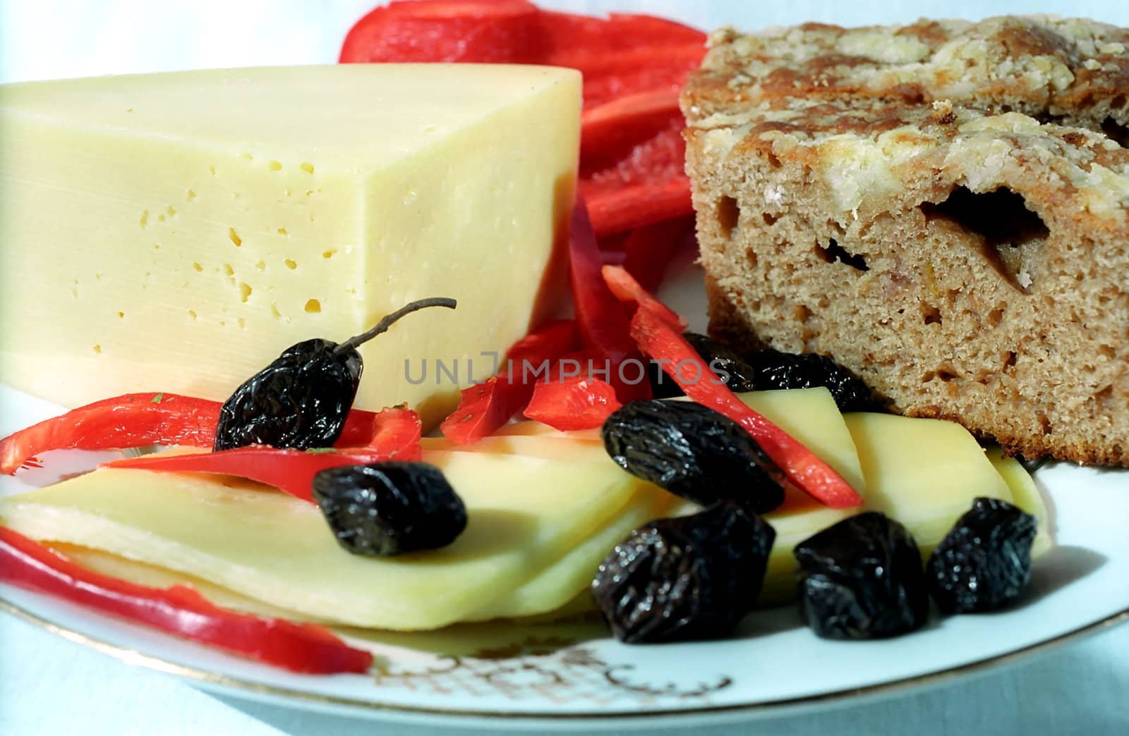 Cheese, black olives, red paprika and farm bread on the plate