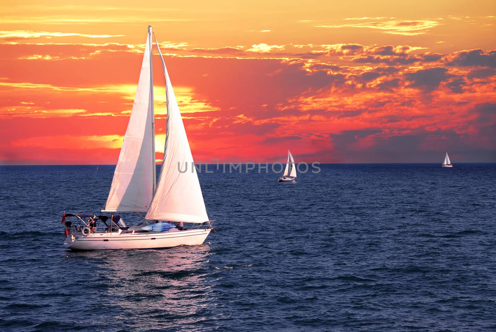 Sailboat sailing on a calm evening with dramatic sunset