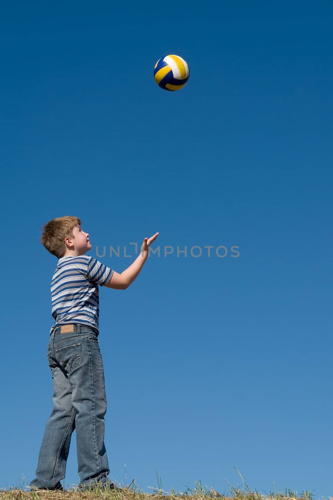 A little boy plays a ball with sky at background