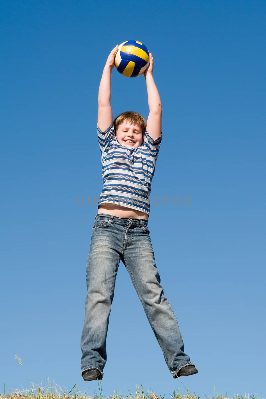 A little boy plays a ball with sky at background