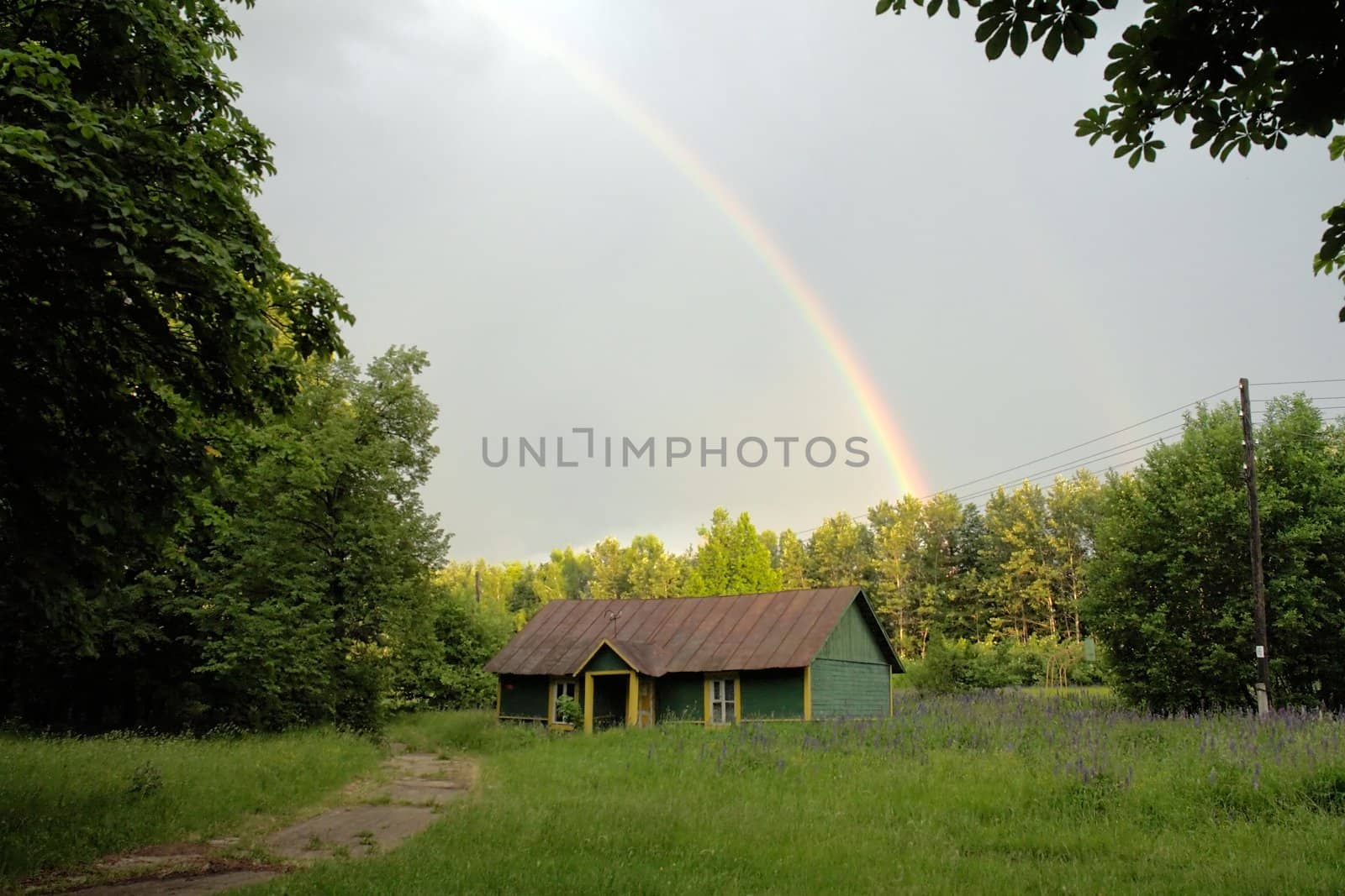 Rainbow after rain above the old house in a forest