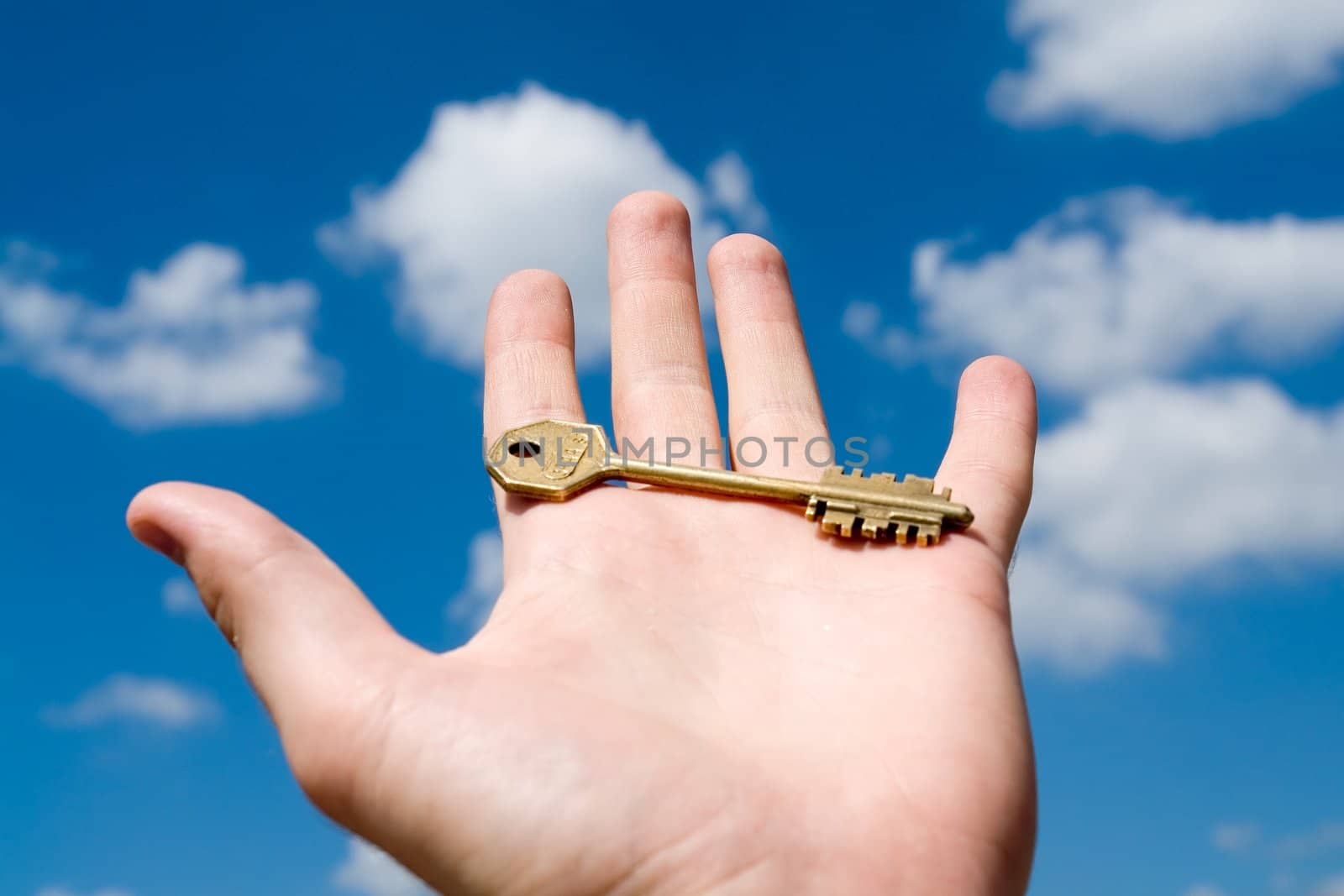 key on the open palm with blue sky at background