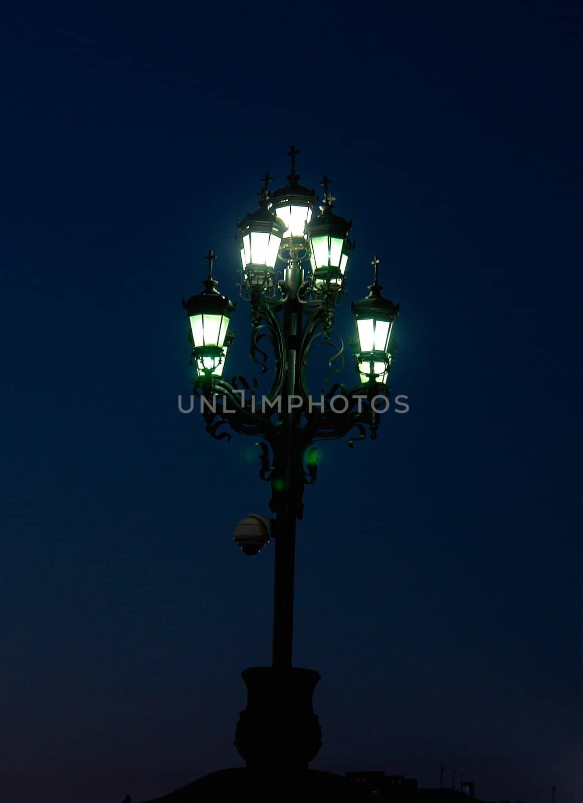 Night. Ancient street lamp emits greenish light.