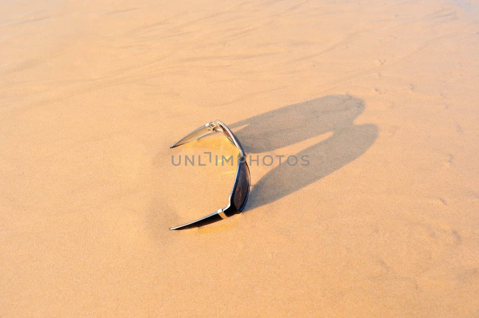 Sun glasses on the sandy beach at the sea