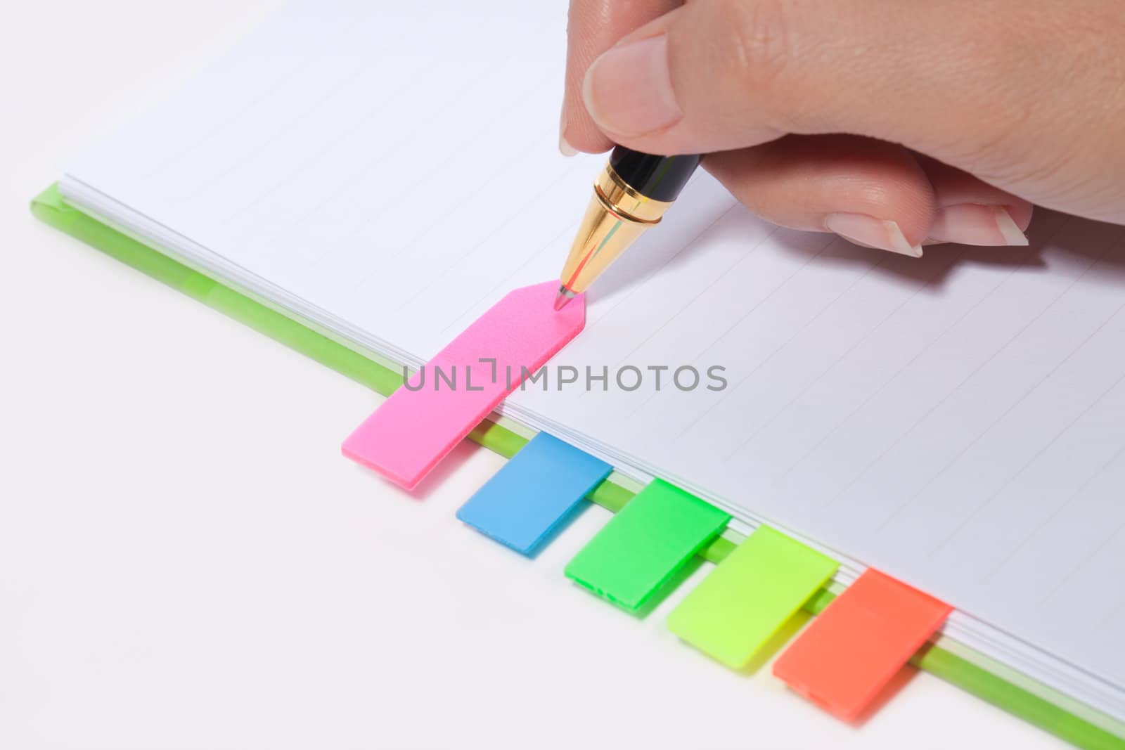 Female hand writing bookmark on notebook by Suriyaphoto