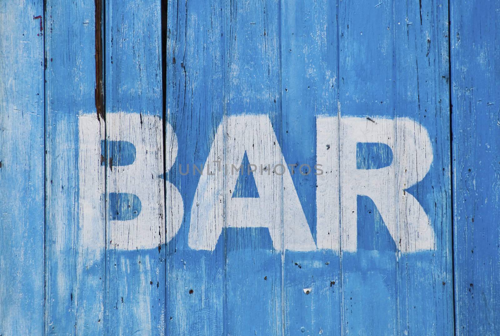 White bar sign painted on a dilapidated blue wooden wall