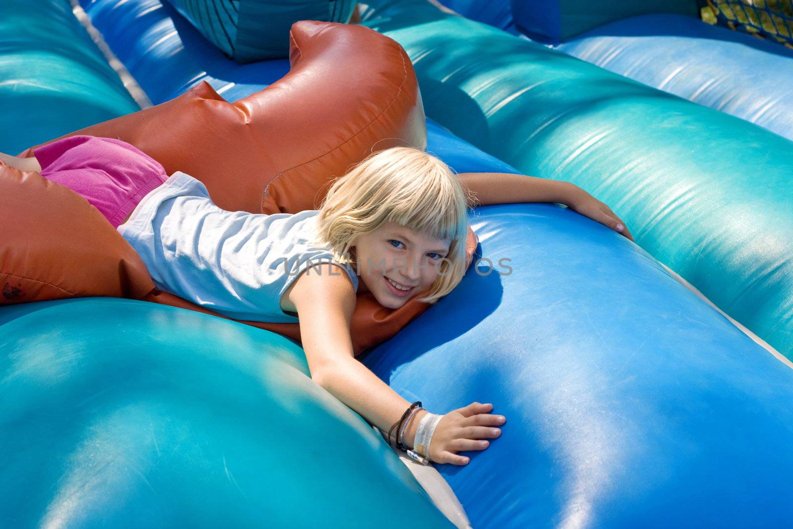 Small blonde girl lying on a inflatable blow-up toy for kid.