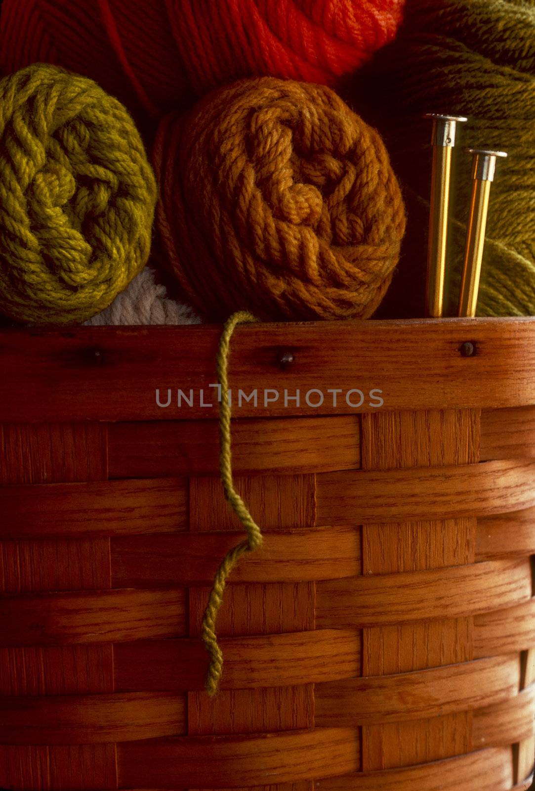 Skeins of wool yarn in a basket with knitting needles