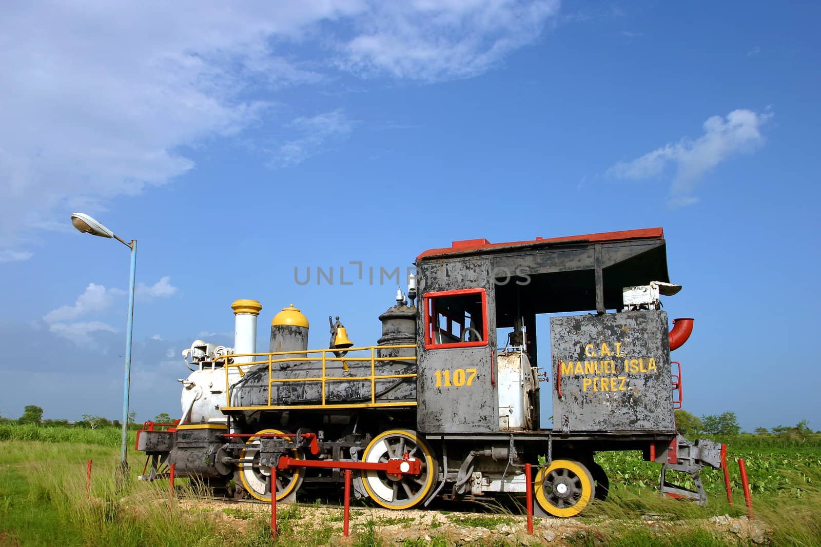 Old steam train rusting in tropical heat and humidity, Cuba under a blue sky