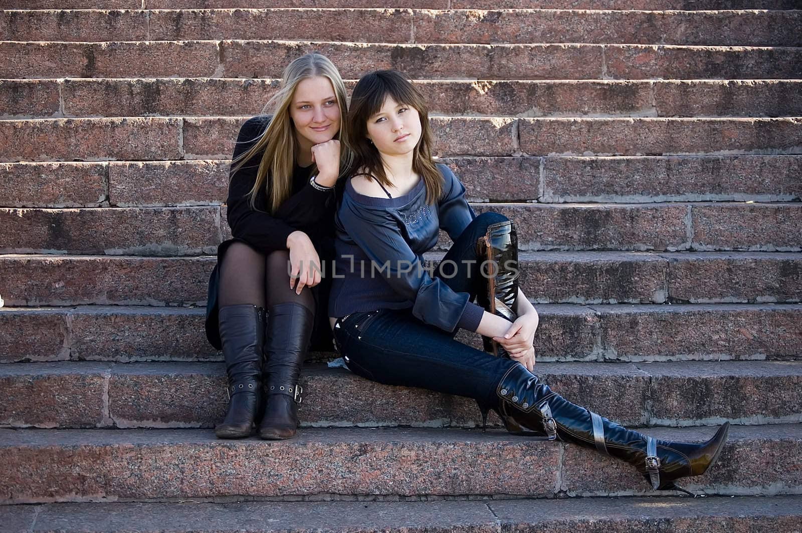 Two girls sit on steps in park