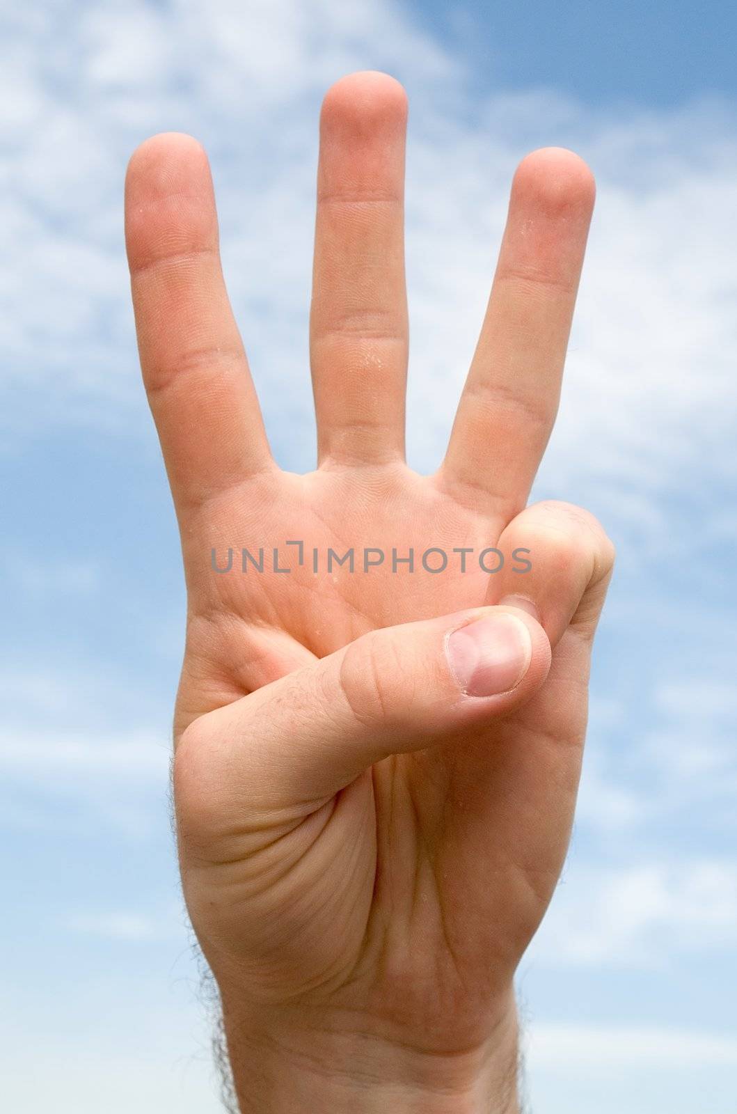 three. hand gesture with blue sky at background