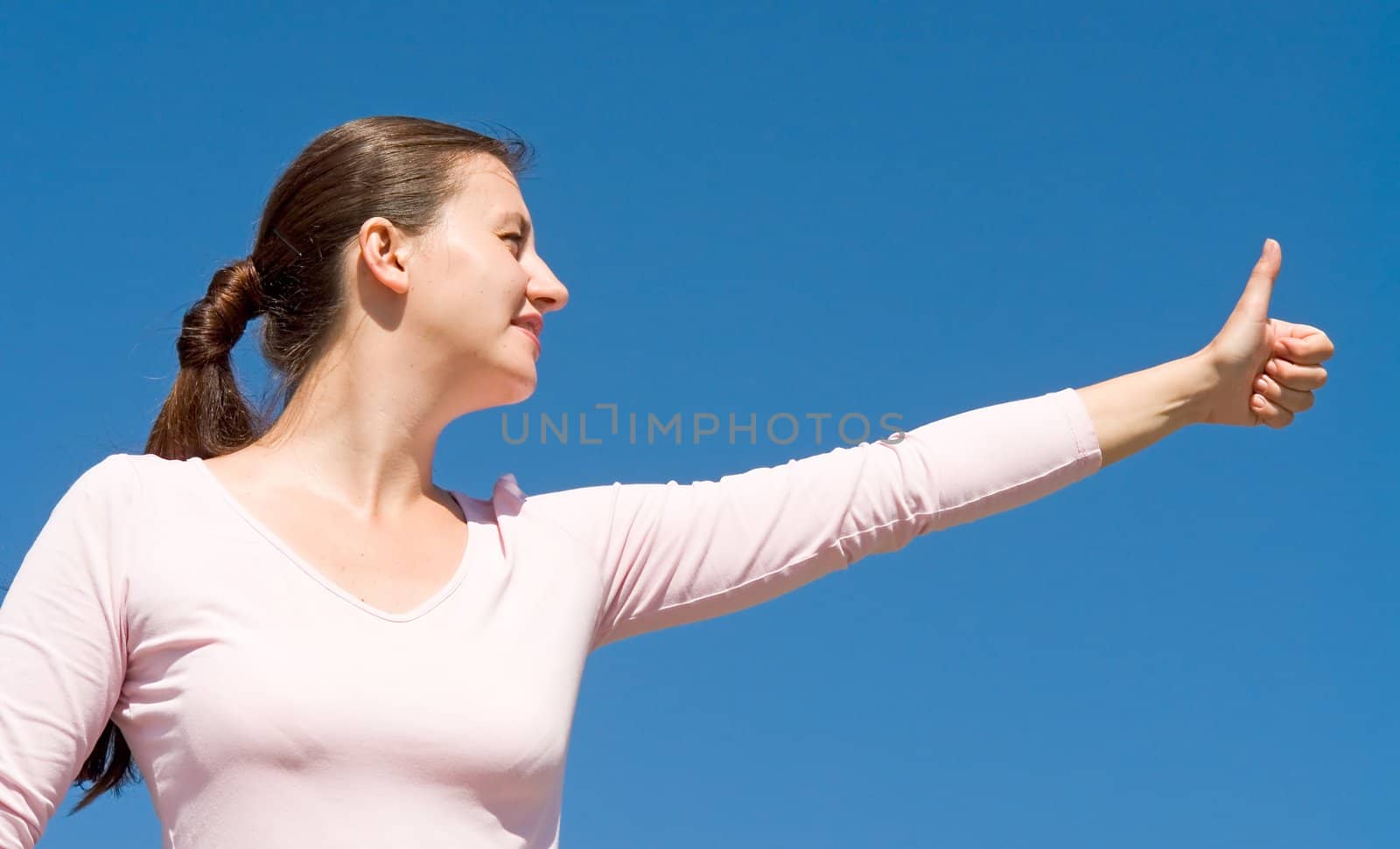 O.K. girl with thumb up on a with sky background