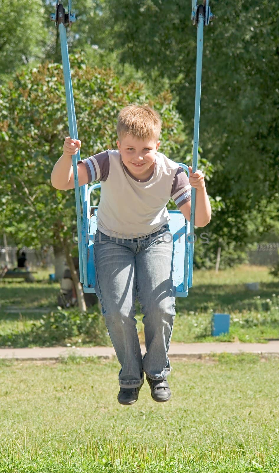 The little boy on a swing in city park