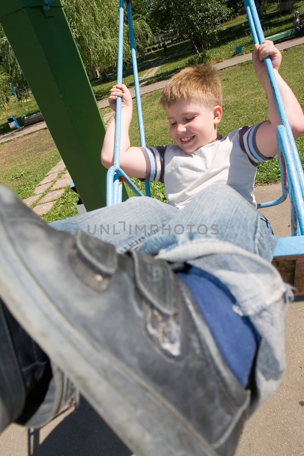 The little boy on a swing in city park