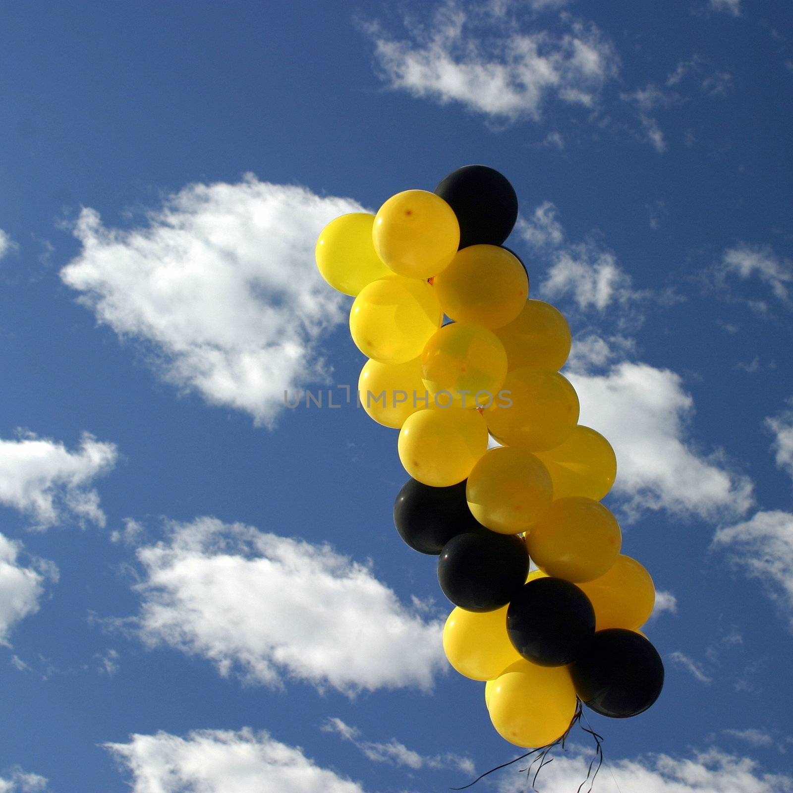 Yellow and black ballons with a blue cloudy sky