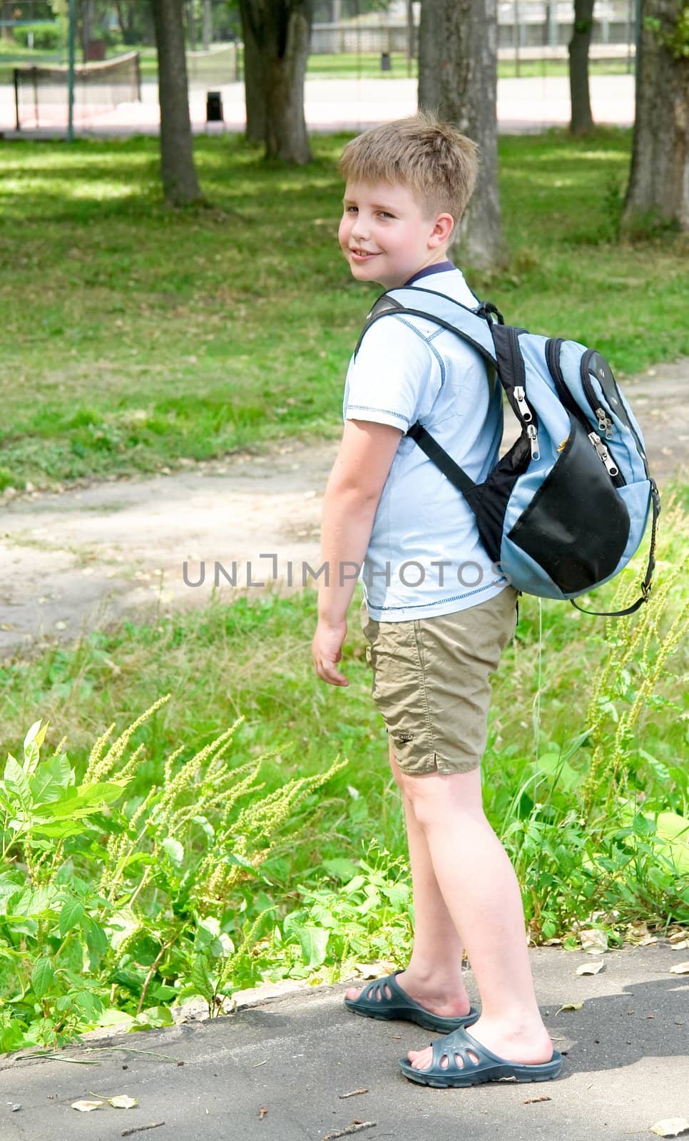 The little boy with a backpack in green park