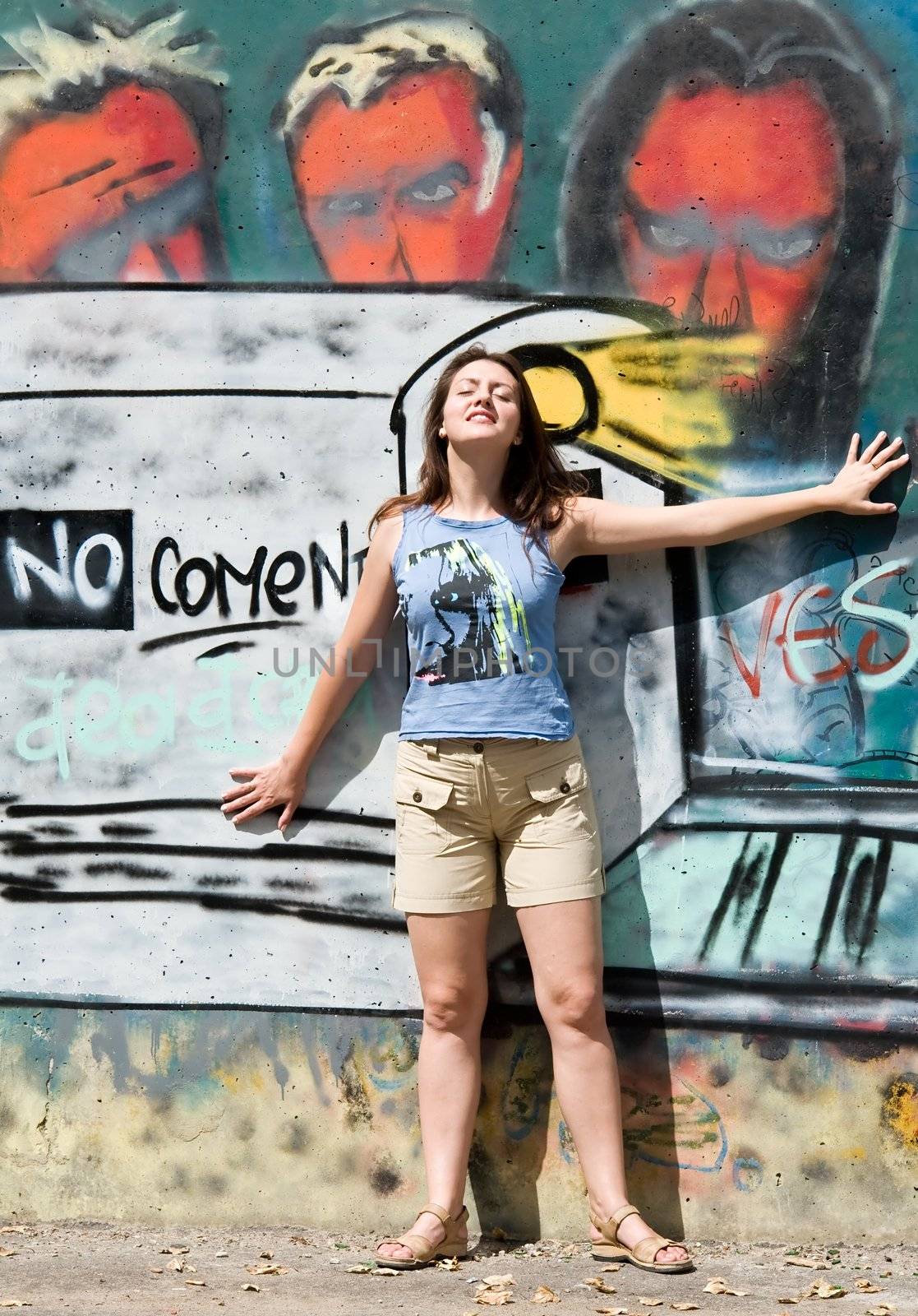 Beautiful young woman in front of grafitti covered wall.