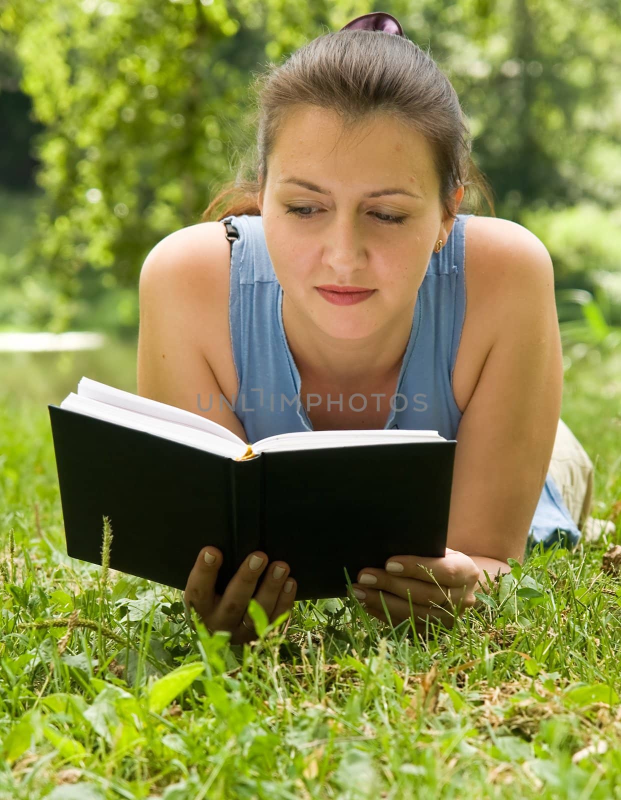 girl reads the book on a lawn in park