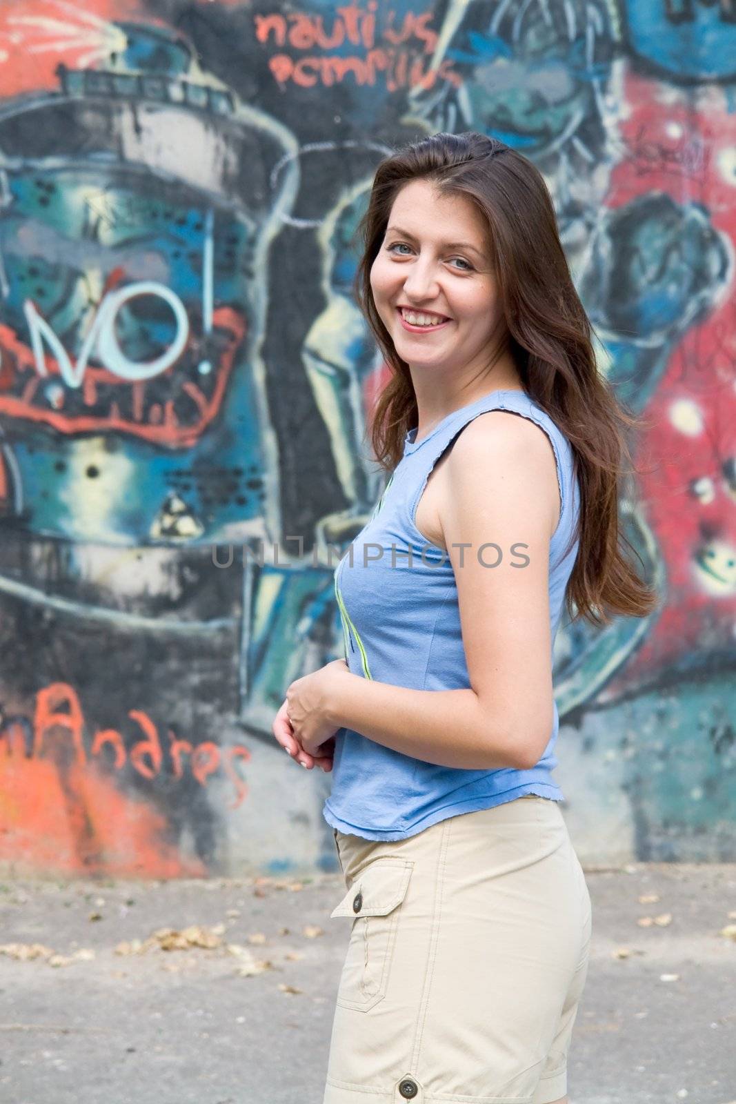 Beautiful young woman in front of grafitti covered wall.