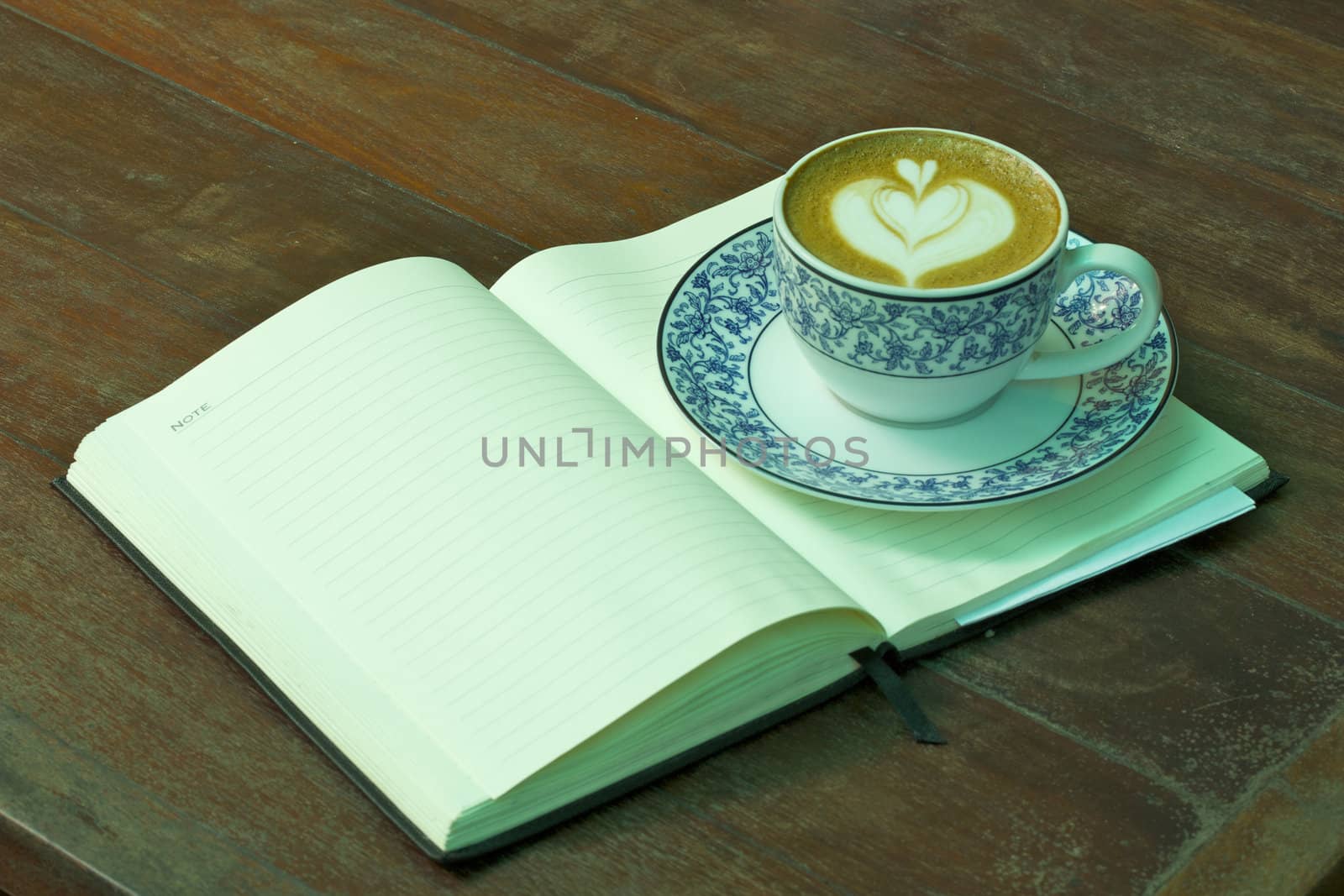 Cup of hot coffee and Notebook on wood table