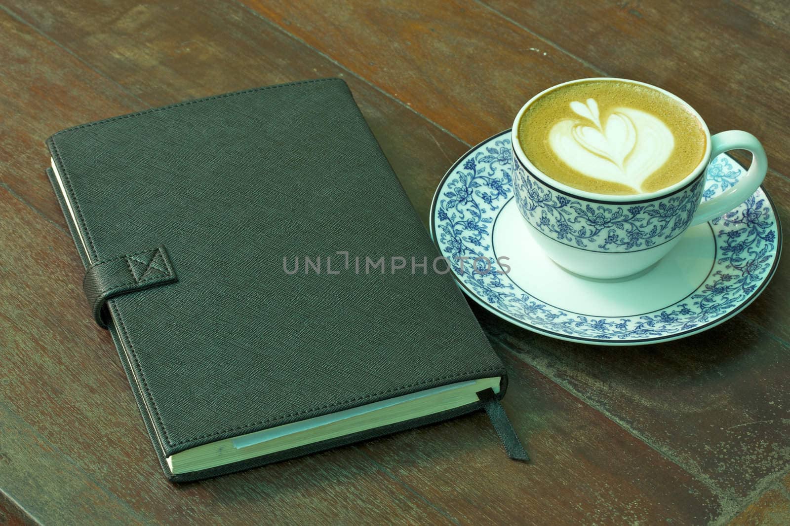 Cup of hot coffee and Notebook on wood table