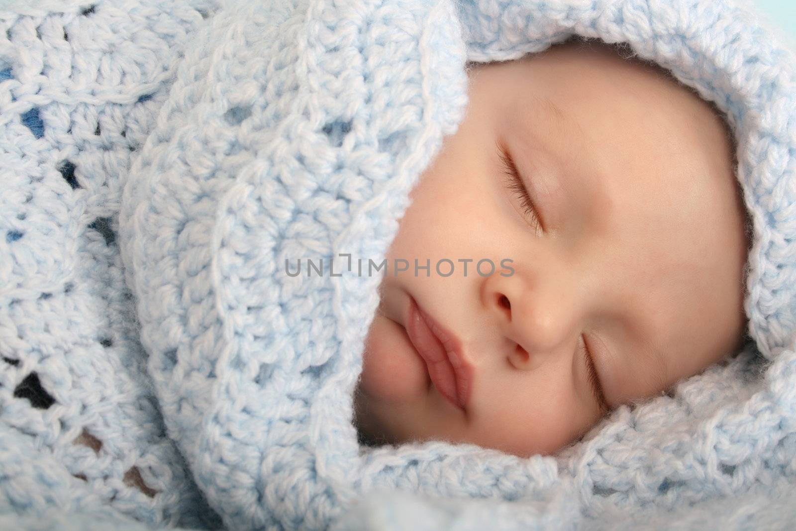 Two month old baby boy wrapped in a blue blanket 