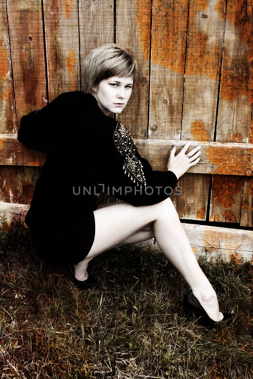 Beautiful blond female leaning against a wooden fence