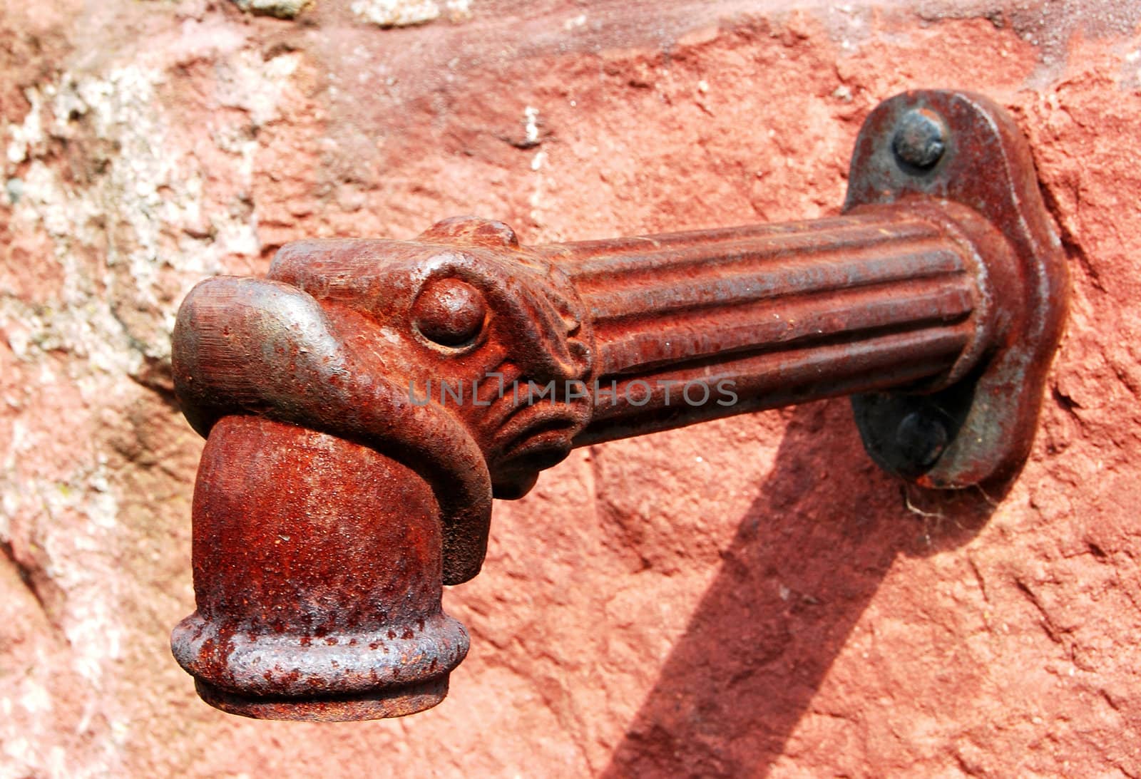 old faucet mounted on a stone, is old, rusty and has a stylized drainage