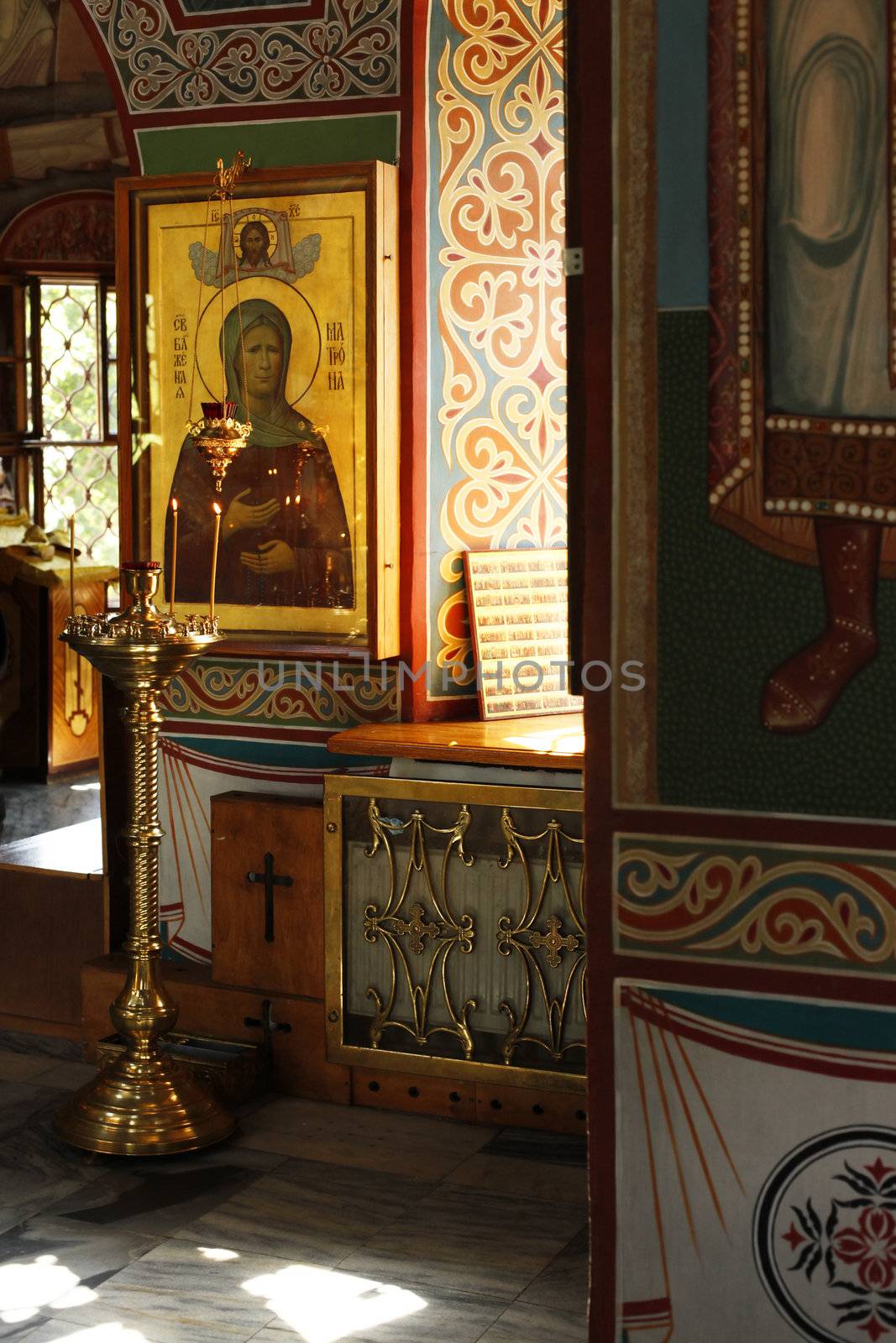 Interior of russian orthodox church. Candles under the ancient icon framed with the gold.