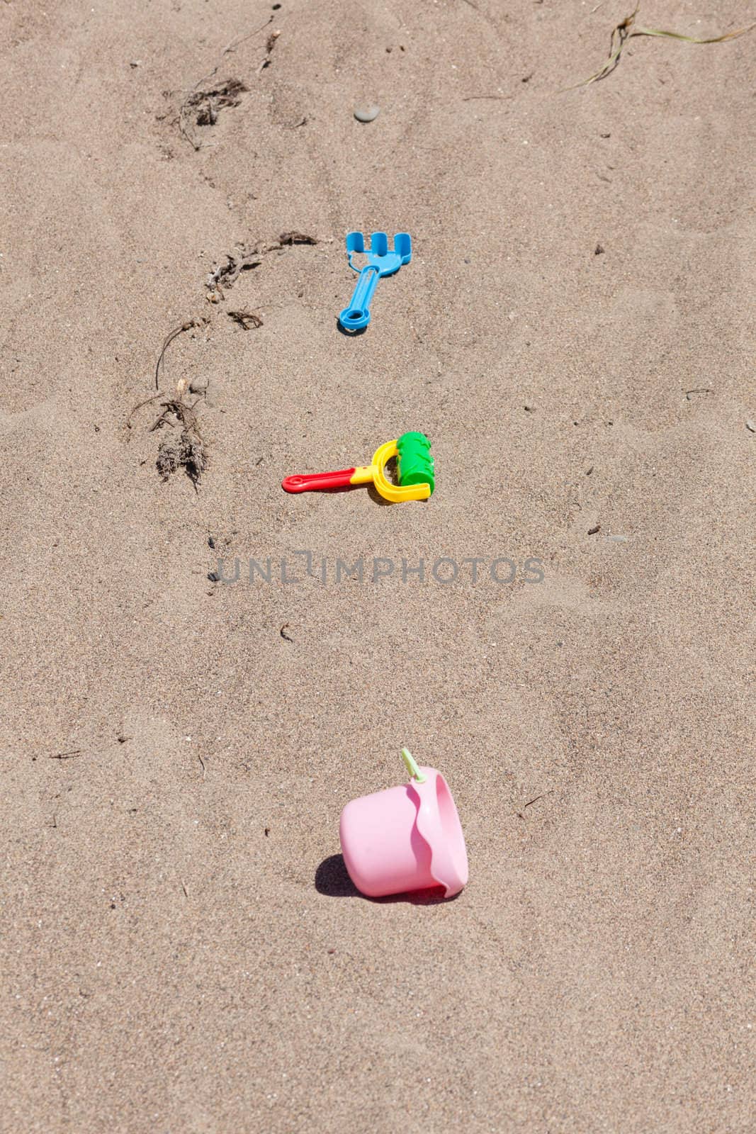 Unorganized colorful plastic beach toys on sand .