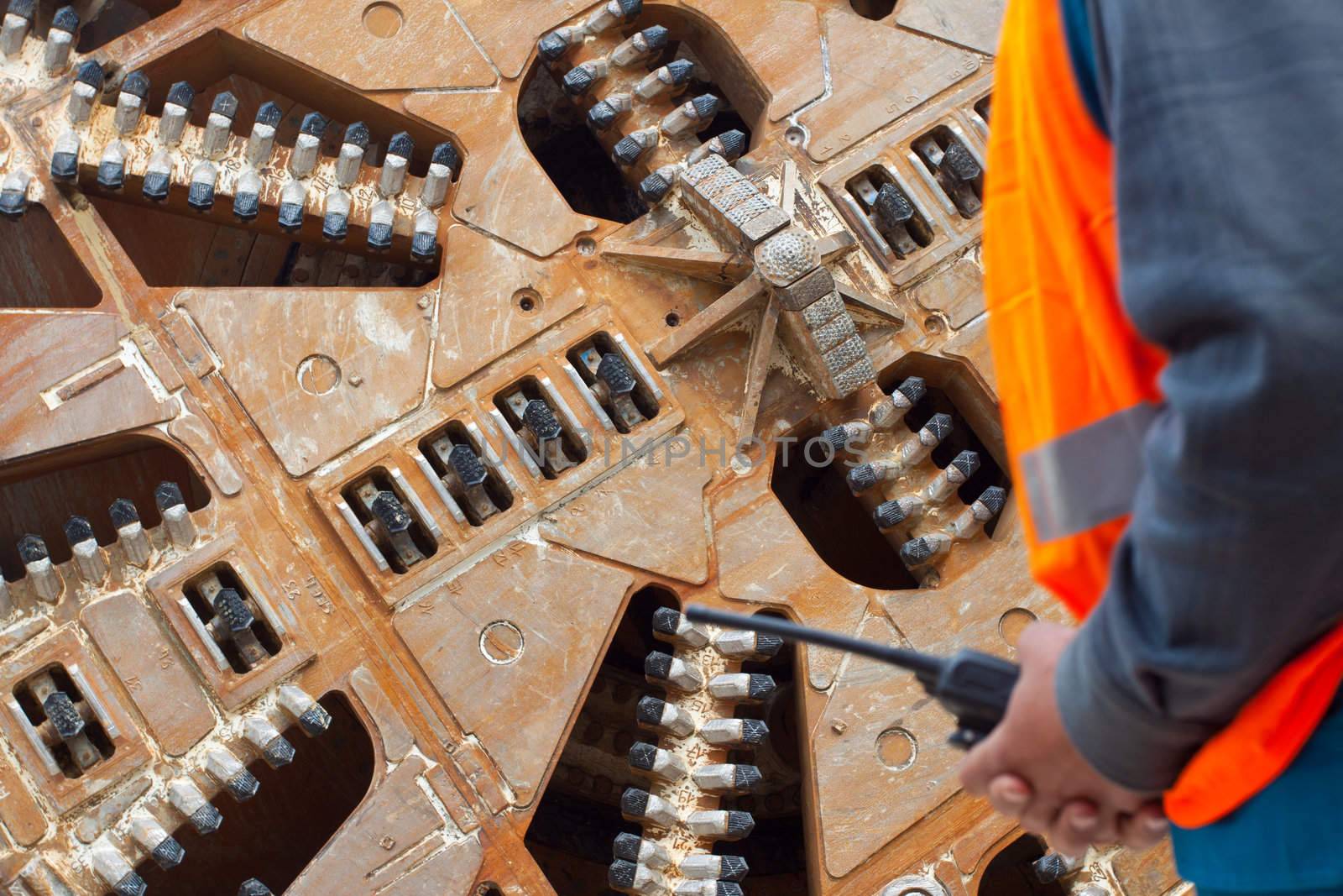 Cropped image of construction worker in front of tunnel boring machine, focus on machine