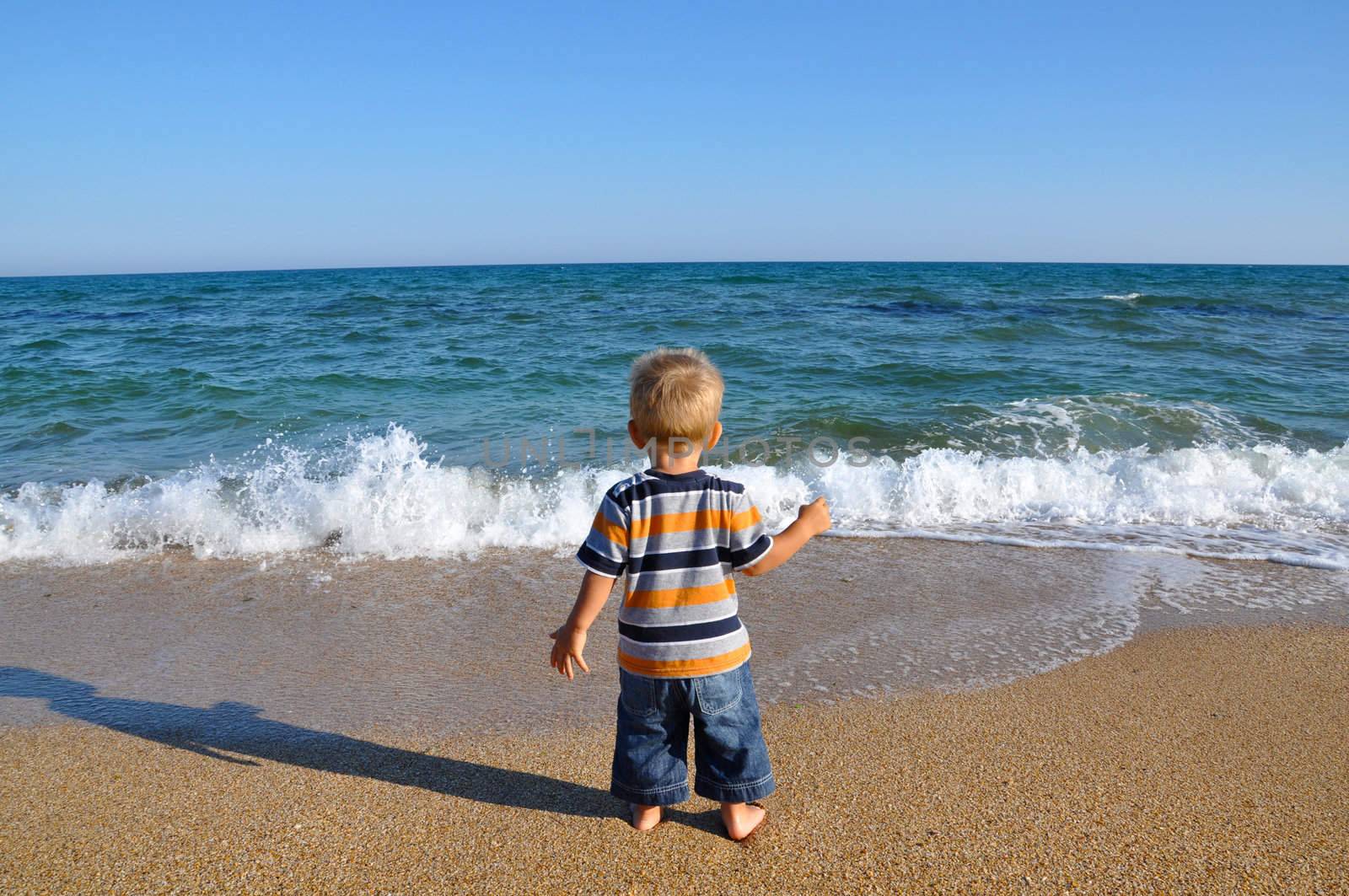 Little blond boy on a sandy beach