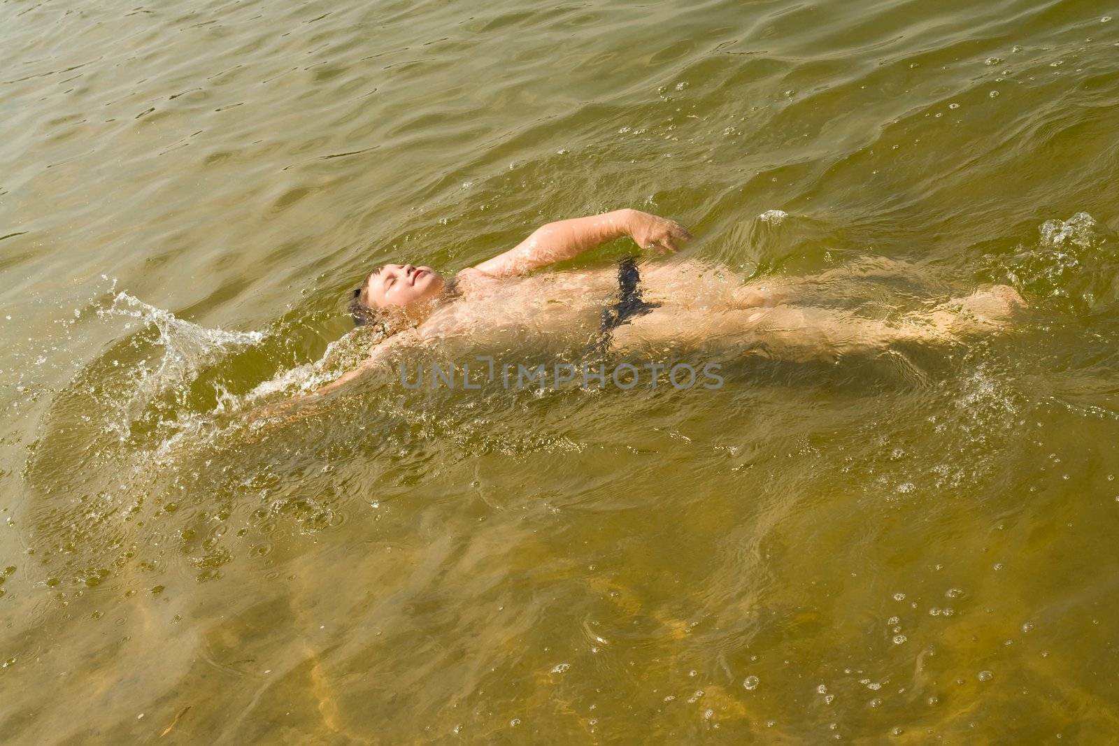 the little boy quickly swims on a back