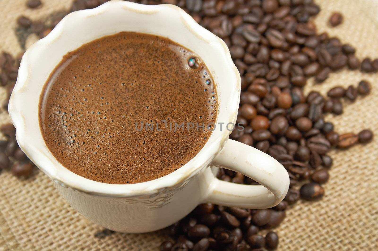 Cup of aromatic coffee and coffee beans on webbing material