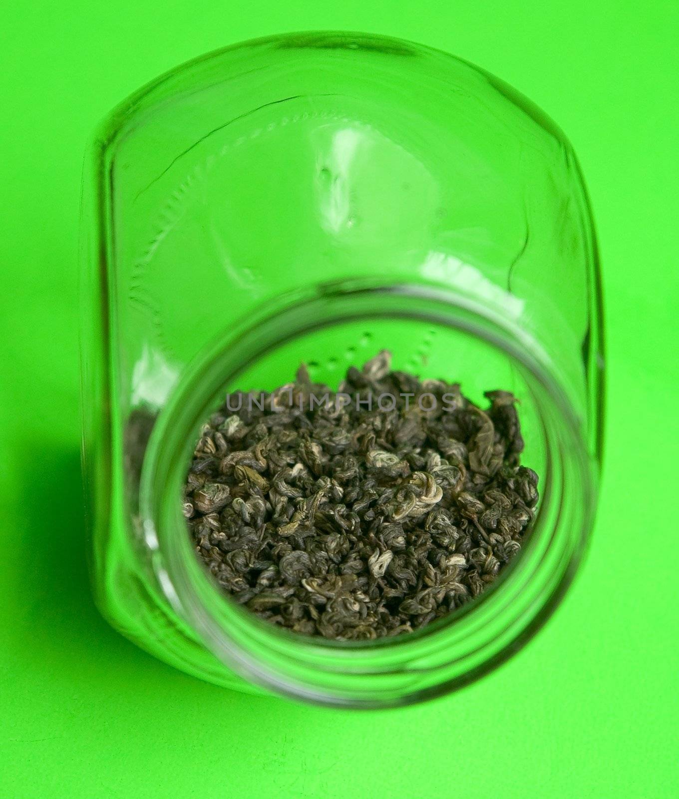 Green tea in glass jar on a green background.