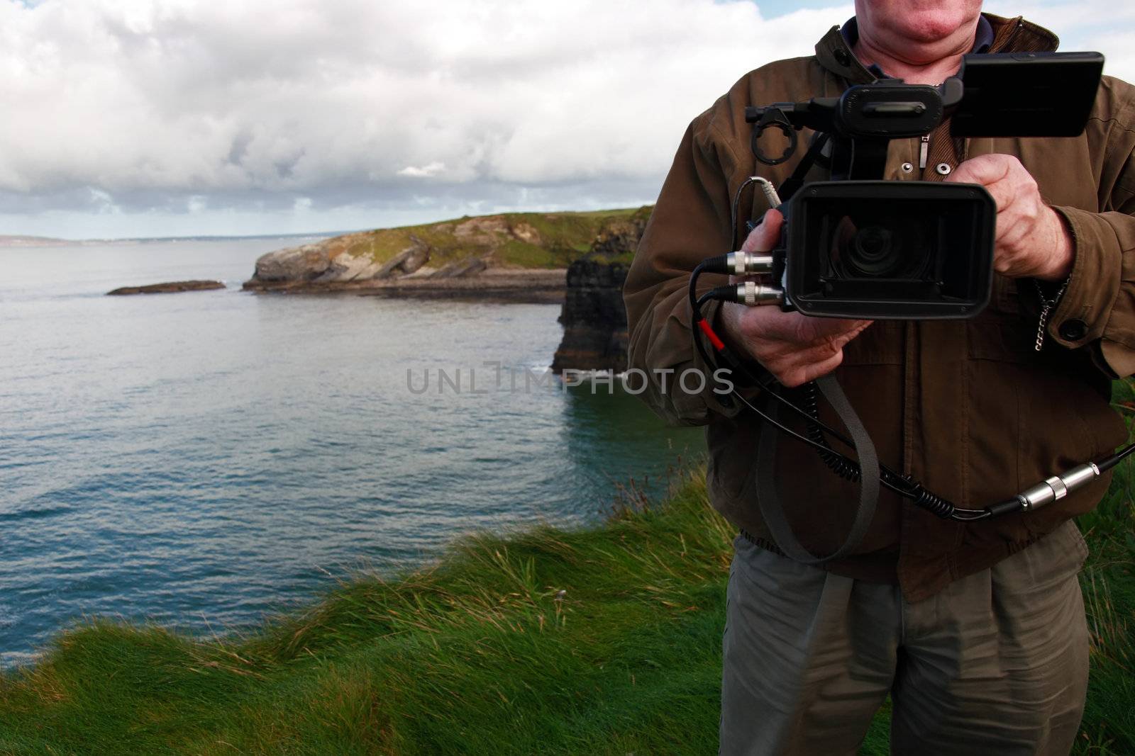 a cameraman filming on the cliff edge in ballybunion ireland