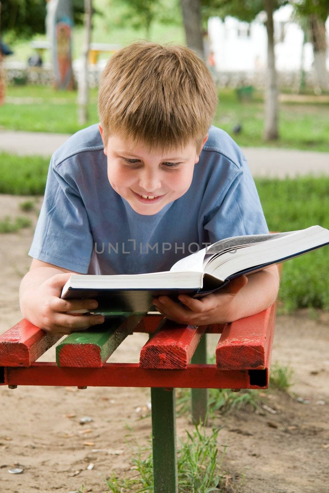 schoolboy reads the book on a bench in park