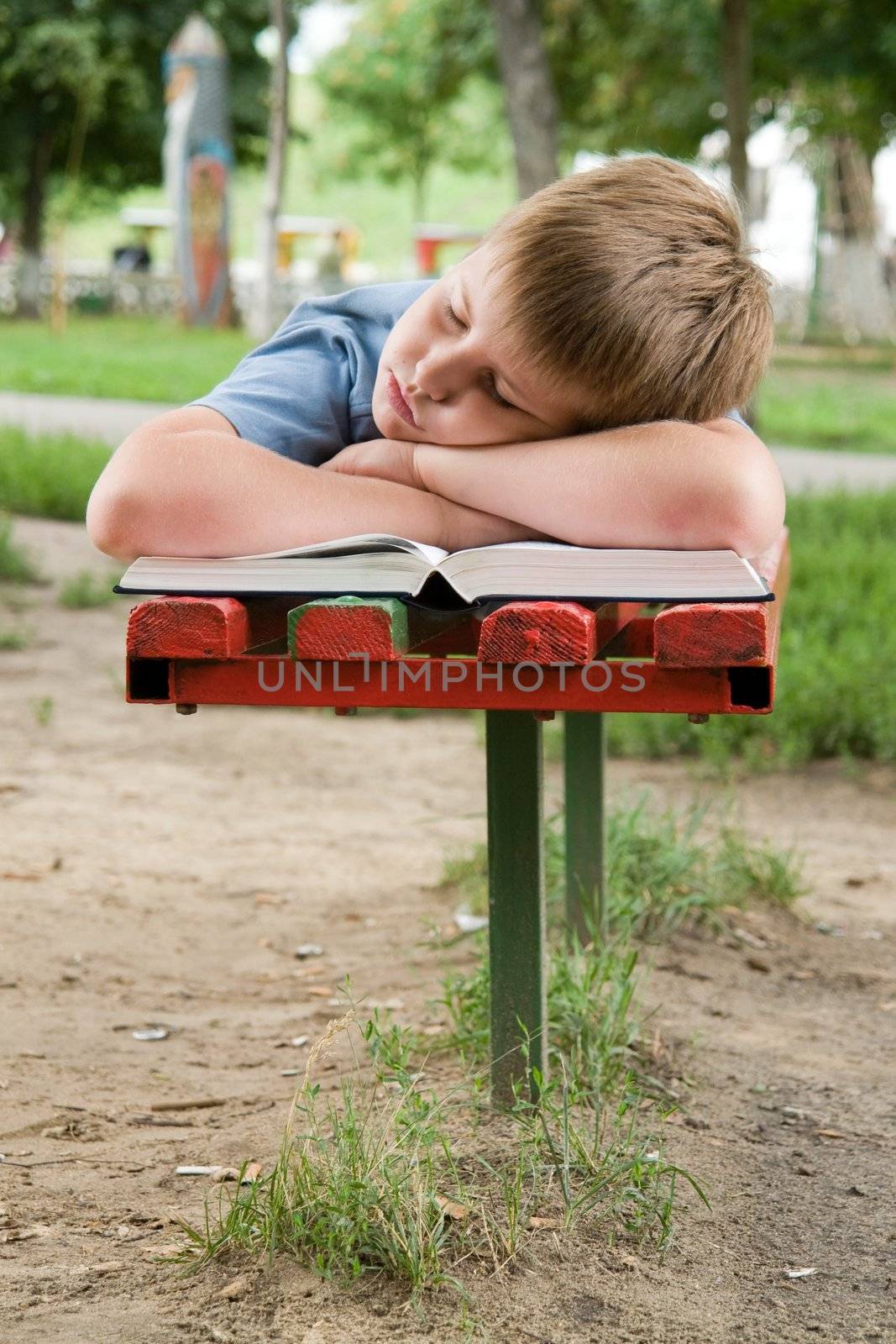 schoolboy sleeps on a bench in park