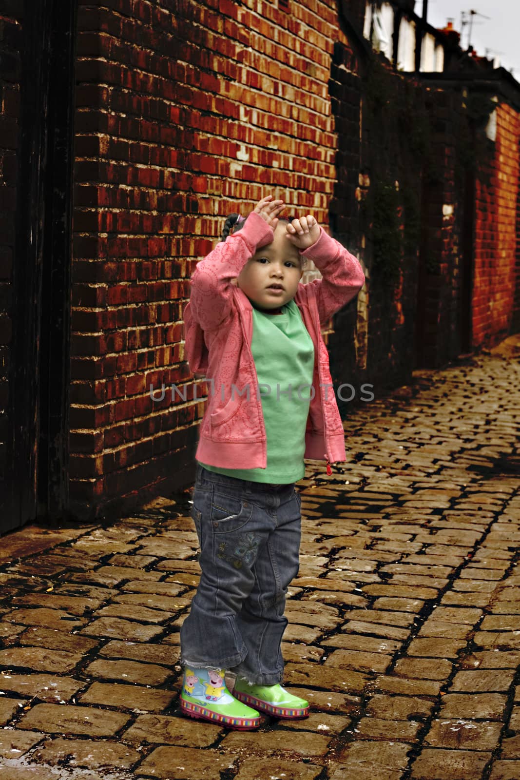 Young black baby girl playing on cobble stoned alley by illu