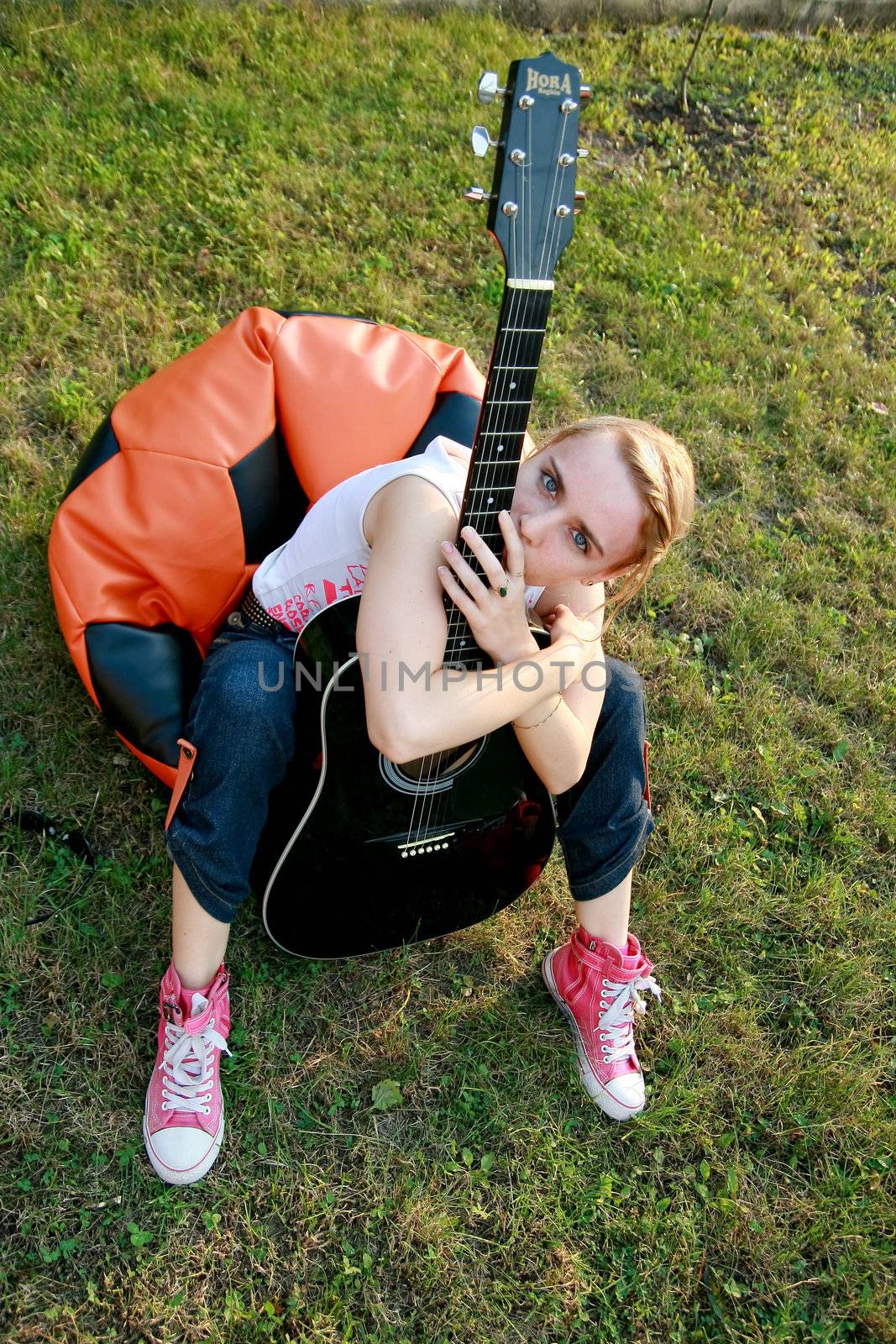 Passionate girl sitting on the grass with a classic guitar in her hands.