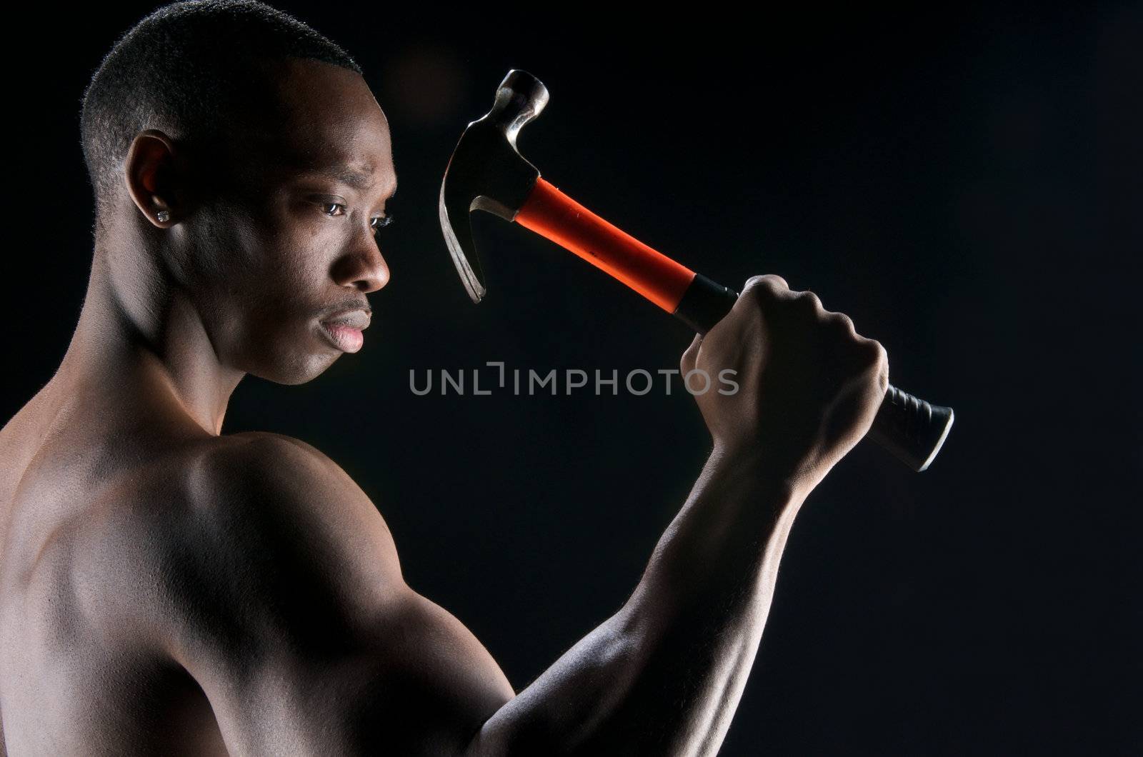 Young african american showing his muscles and ready to work with hammer.