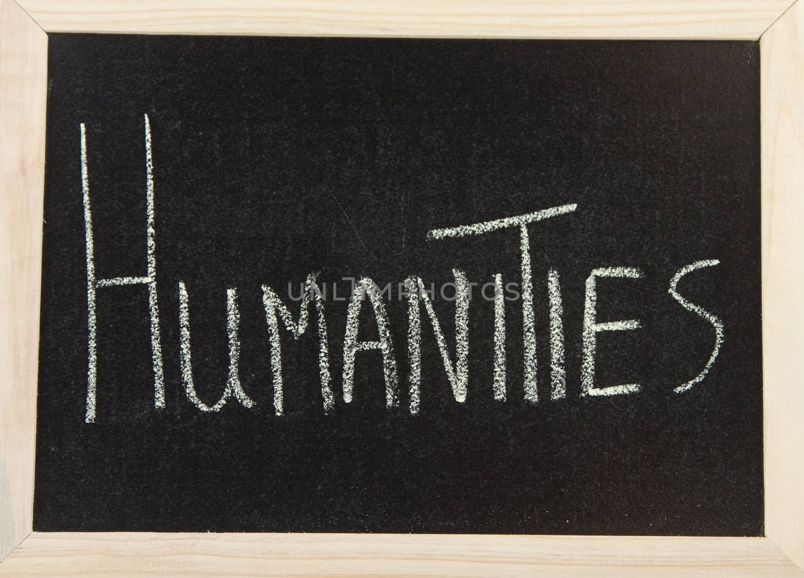 A black board with a wooden frame and the words 'HUMANITIES' written in chalk.