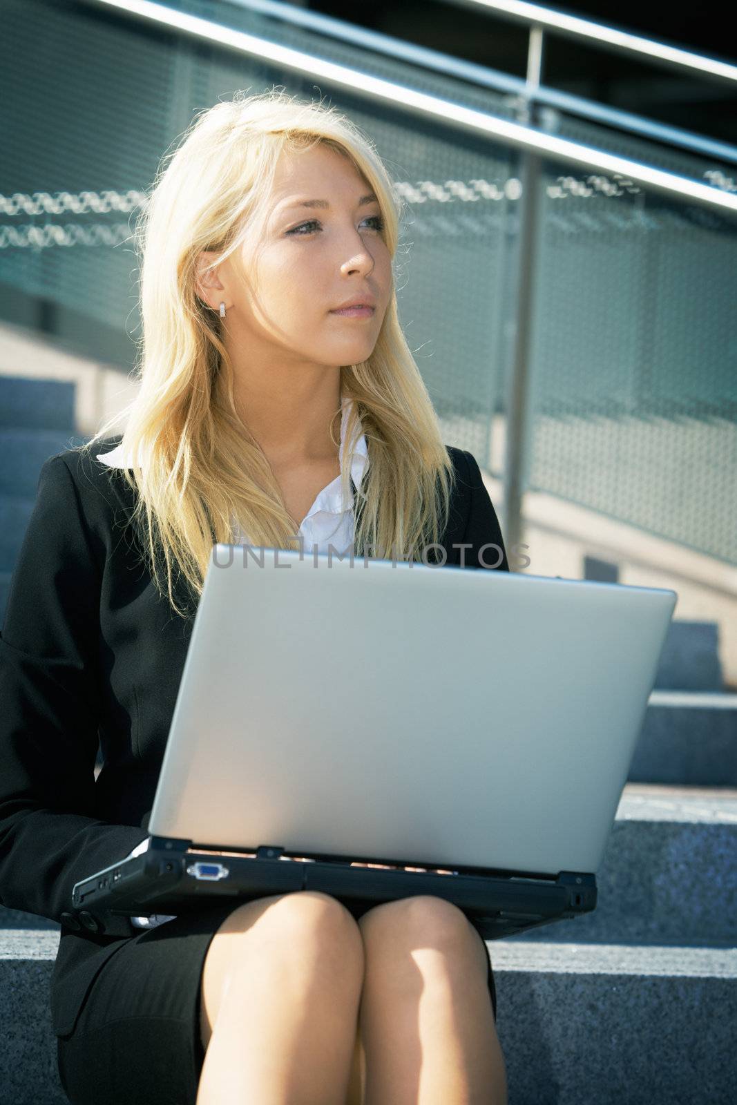 Young businesswoman using laptop computer in city, sitting on stairway