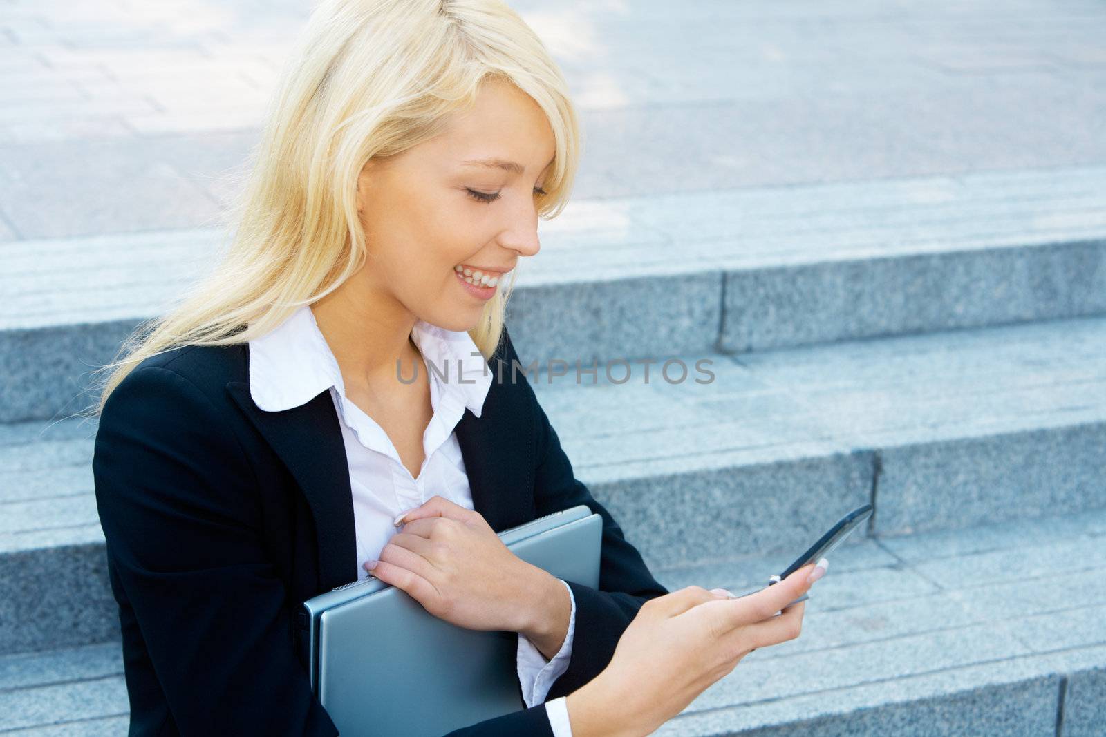 Young businesswoman sitting on stairway, looking at cell phone