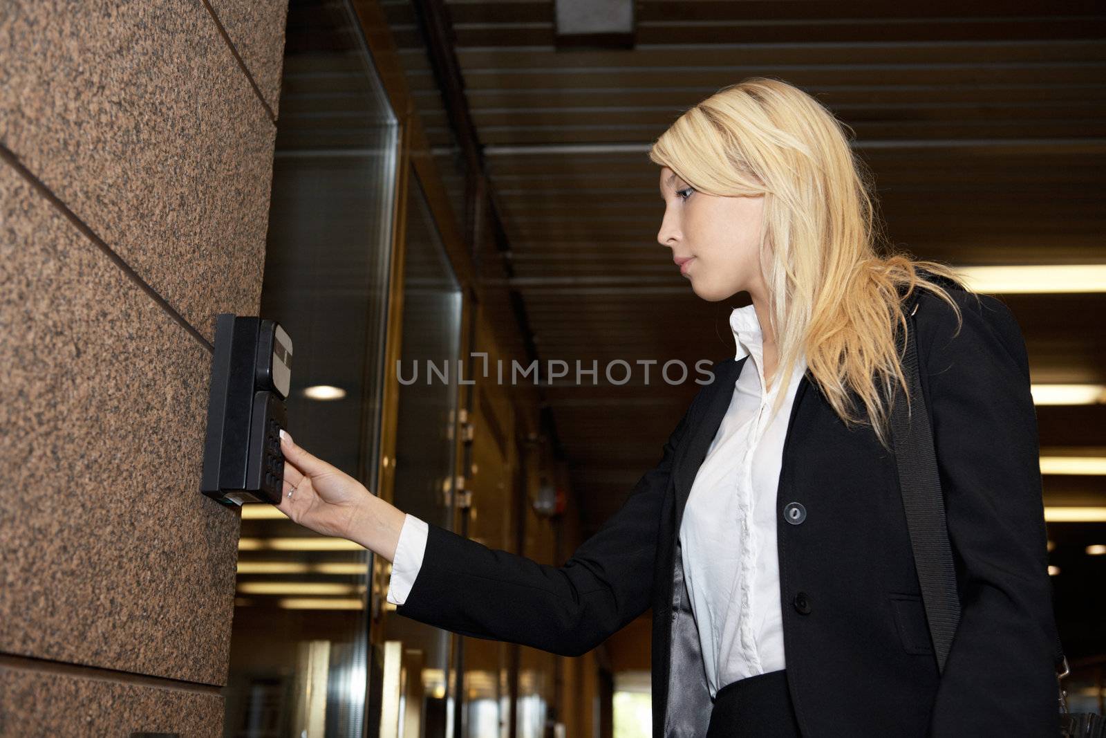 Young businesswoman entering access code at building entrance