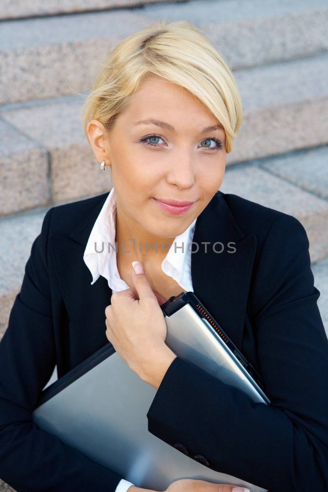 Businesswoman holding laptop computer, looking at camera
