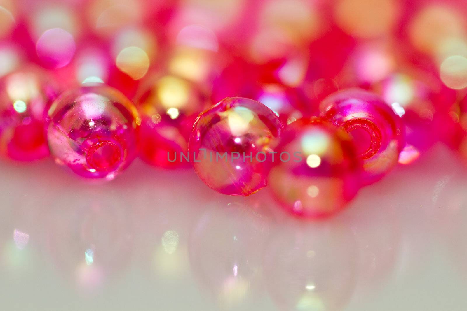 Red beads on white surface with mirror image