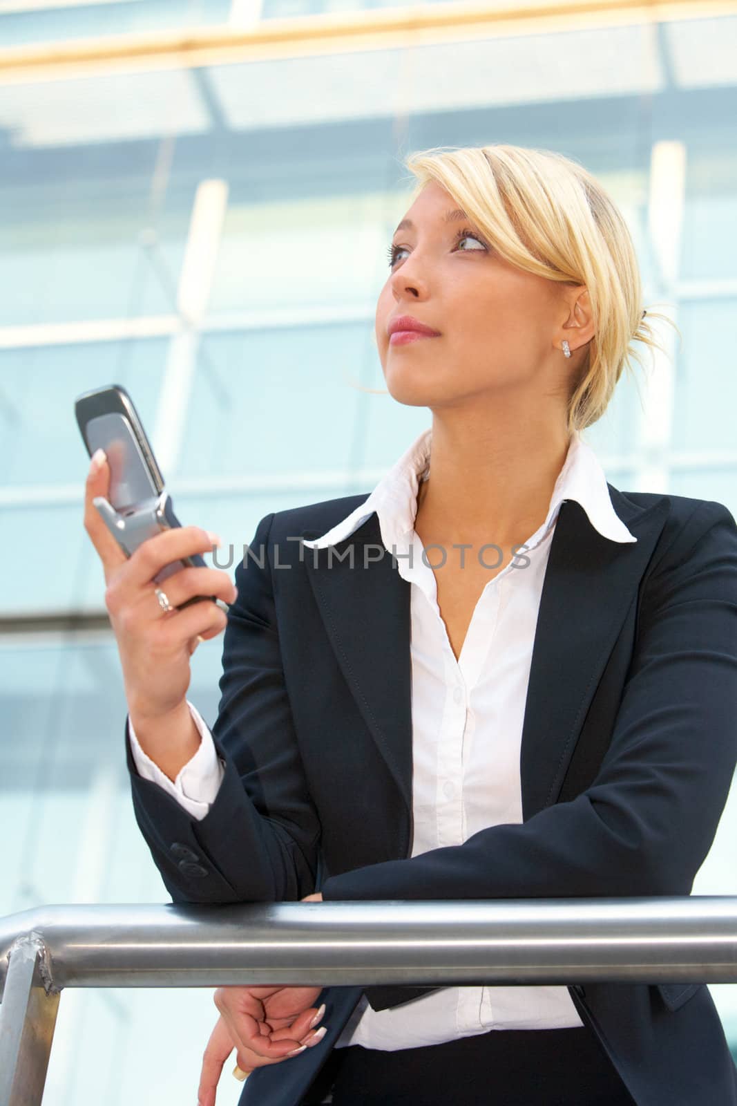 Businesswoman holding mobile phone, looking up